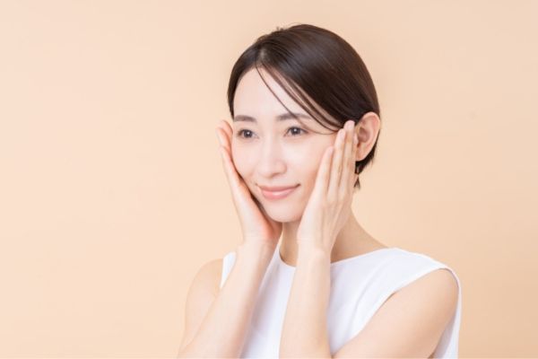 両手でほほを触る女性