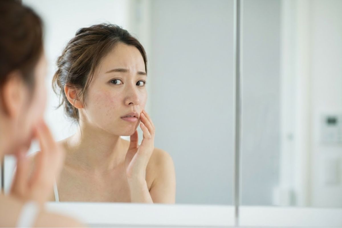 鏡をみる肌悩みのある女性